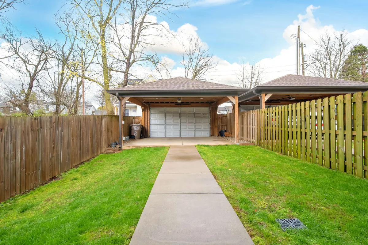 A sunlit exterior view showcasing a green lawn, pathway, and fenced backyard area. The open, inviting space is ideal for group games, outdoor gatherings, or simply enjoying a peaceful moment in the heart of the city.