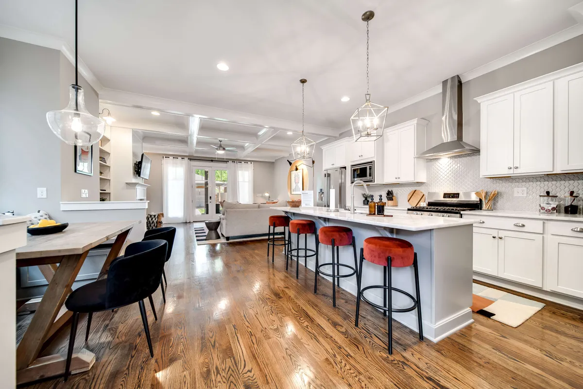 The image showcases a stylish, open-concept kitchen and dining area, featuring a spacious kitchen island with comfortable seating, gleaming stainless steel appliances, modern light fixtures, and a large dining table. The layout feels both luxurious and welcoming, perfect for group gatherings and memorable meals.