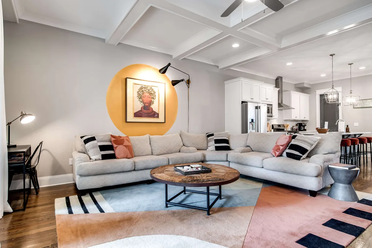 This image shows a large, cozy sectional sofa with decorative artwork on the wall and a coffee table in the center. The setting invites relaxation, socializing, and entertaining, embodying family togetherness after a day out.