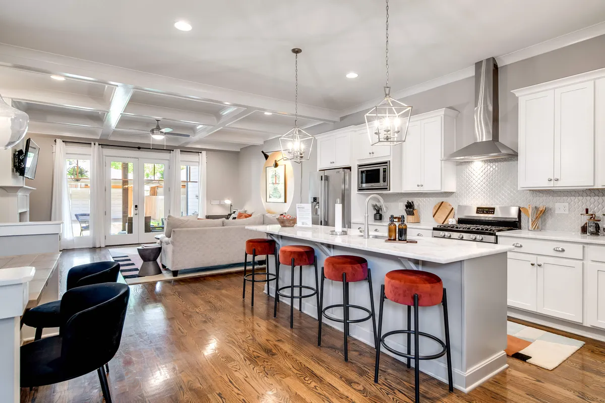A spacious kitchen featuring a central island with pendant lights, modern appliances, and an open layout that connects seamlessly to the dining and living areas. The setting is vibrant, inviting, and showcases ample space for group cooking and entertaining.