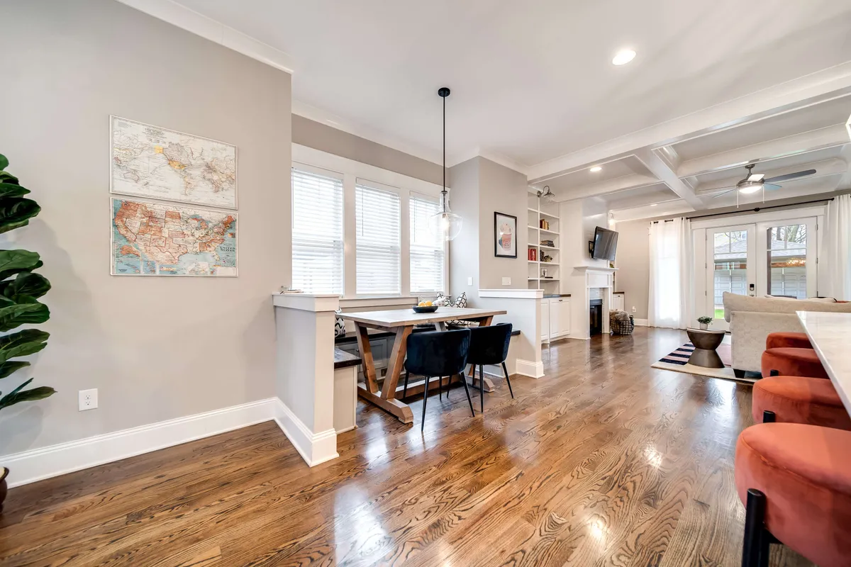 An open-concept space with a cozy seating area adjacent to a dining table, illuminated by large windows that let in abundant natural light. A map on the wall and city views outside reinforce the urban yet homey vibe.